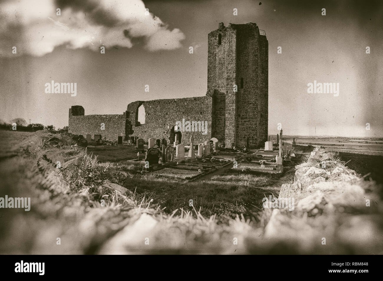 Alte Kirche Ruinen mit kleinen Friedhof umgeben mit Steinmauer in Sepia Stockfoto