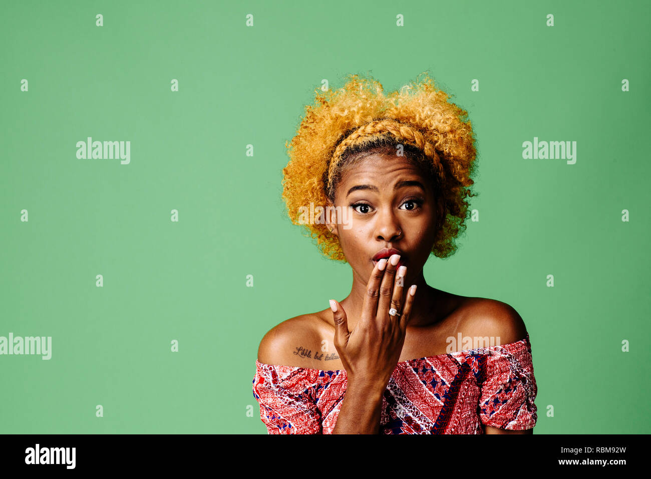 Junge Frau mit einem entsetzten Ausdruck in die Kamera schaut, auf grüner studio Hintergrund isoliert Stockfoto