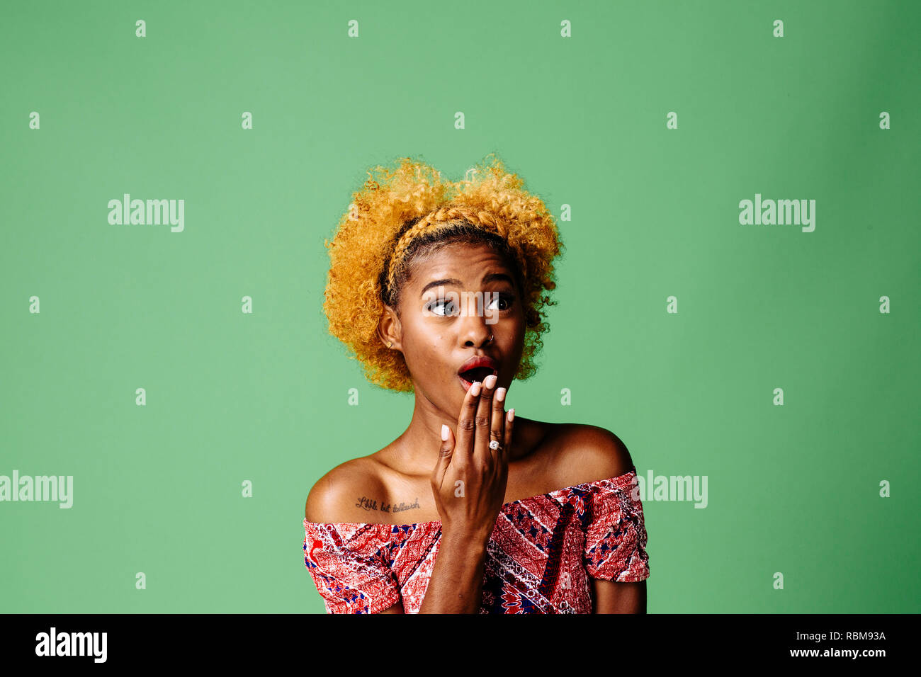 Junge Frau mit einem entsetzten Ausdruck suchen nach etwas, auf grüner studio Hintergrund isoliert Stockfoto