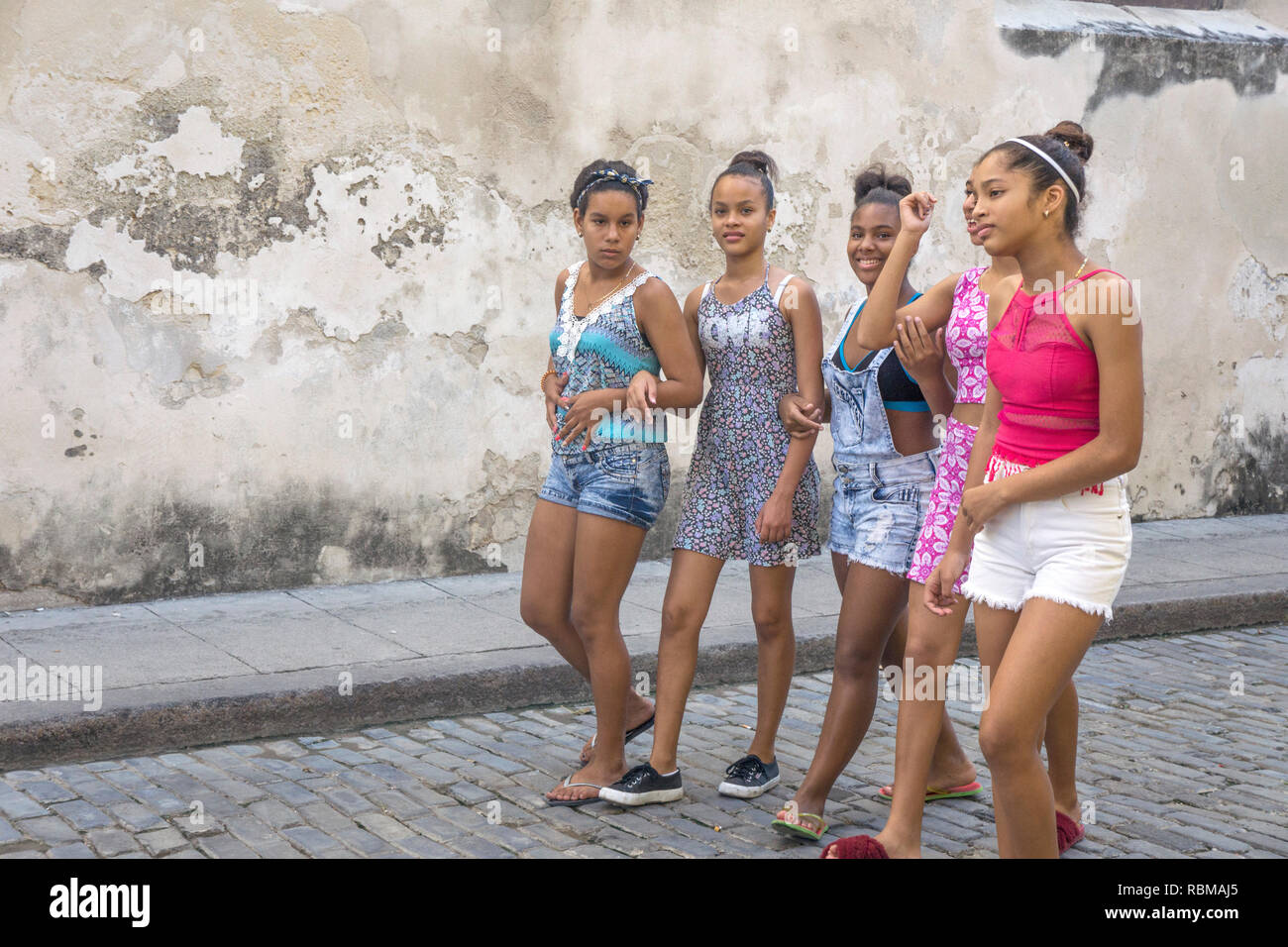 Lächelnd Gruppe von ziemlich Kubanische Jugendliche, Arme ab, Rückkehr von Touristen, die in der Kathedrale von Havanna Plaza durch Horden von Touristen frequentiert Stockfoto