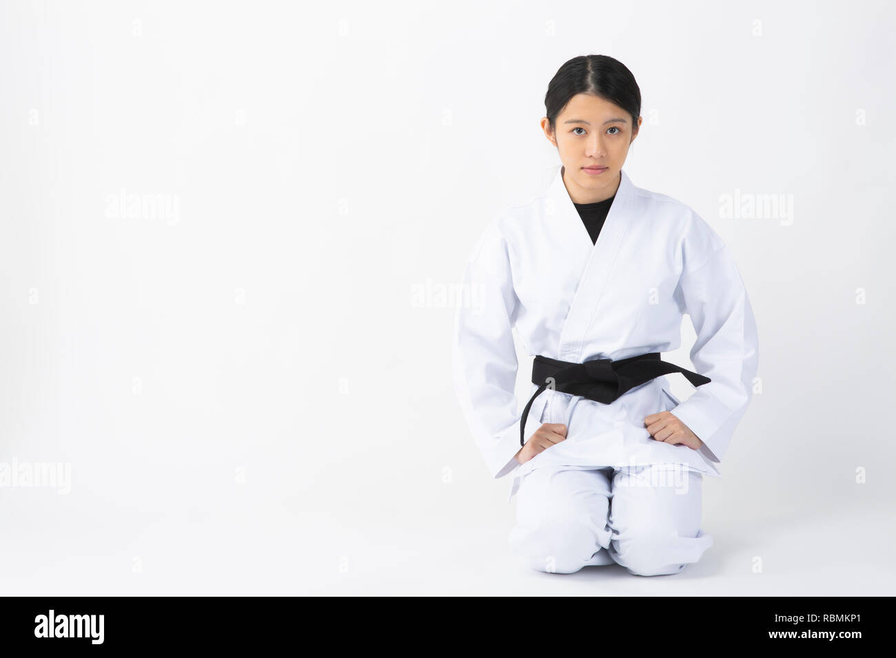 Junge Frau mit Karate Anzug an Kamera starrt auf weißem Hintergrund Stockfoto