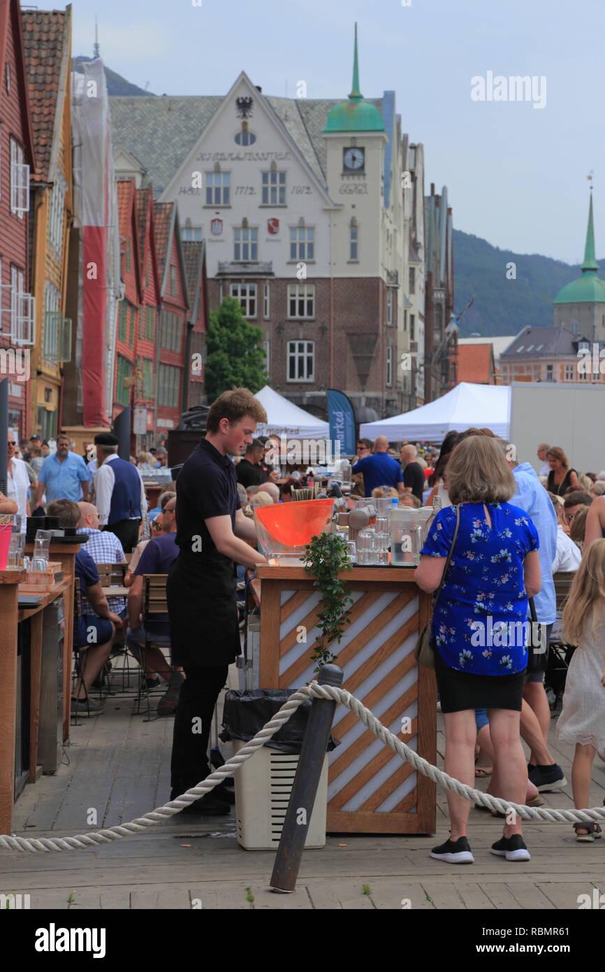 Ein Mann bedient Kunden an einer im Restaurant- und Barbereich auf der UNESCO-Welterbestätte Bryggen, während der Markt Tag in Bergen, Norwegen. Stockfoto