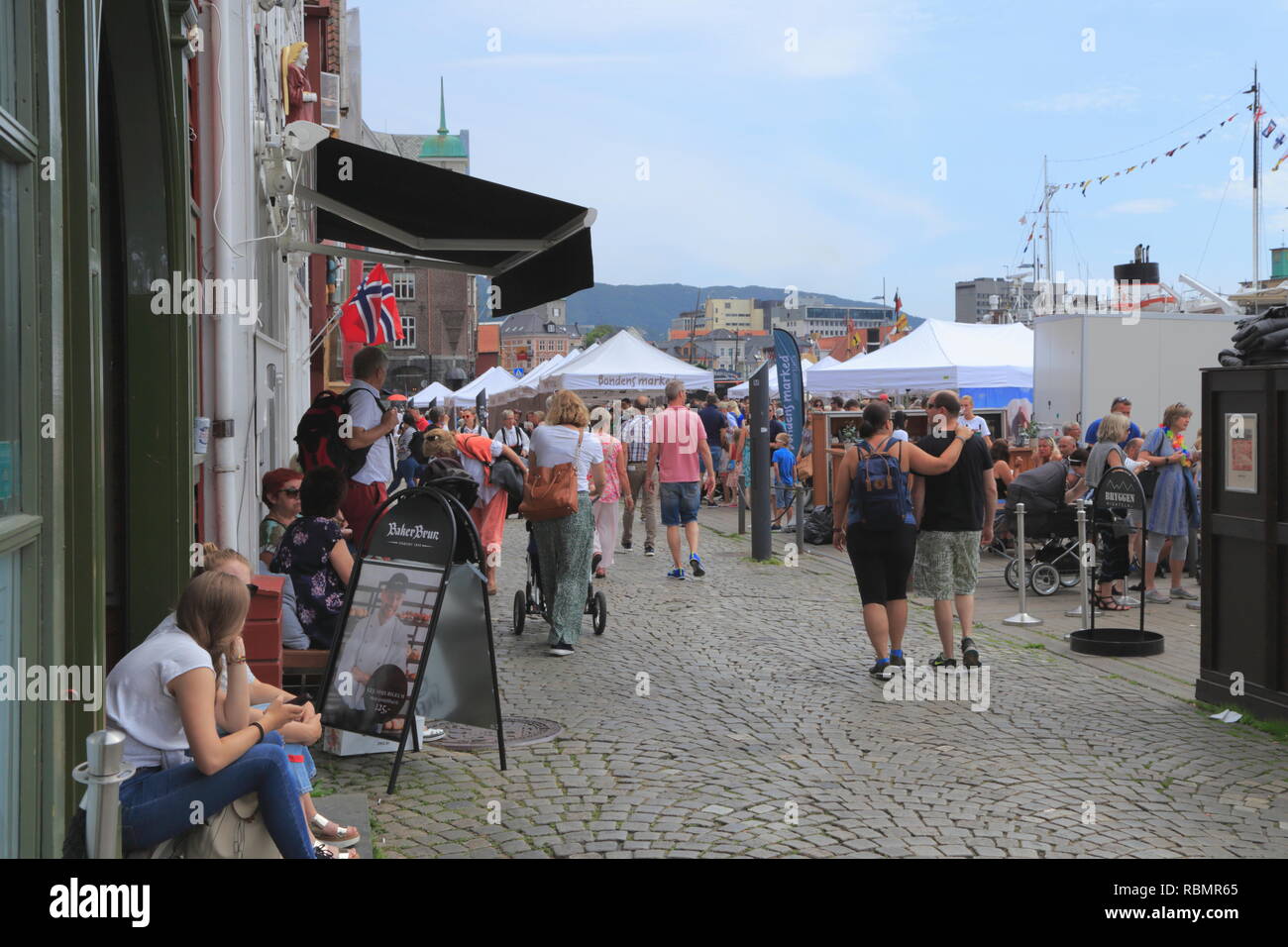 Die Leute sitzen und zu Fuß entlang der UNESCO Weltkulturerbe Bryggen, während des traditionellen Torgdagen (Markt) in Bergen, Norwegen. Stockfoto