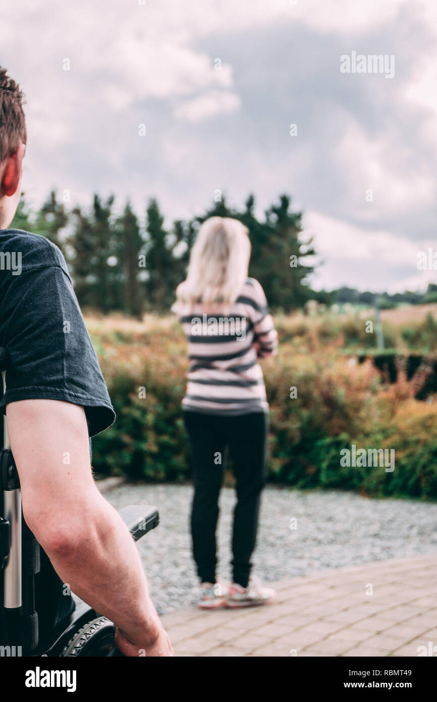 Mann mit dystonie im Rollstuhl und Frau in Beziehung Kampf Stockfoto