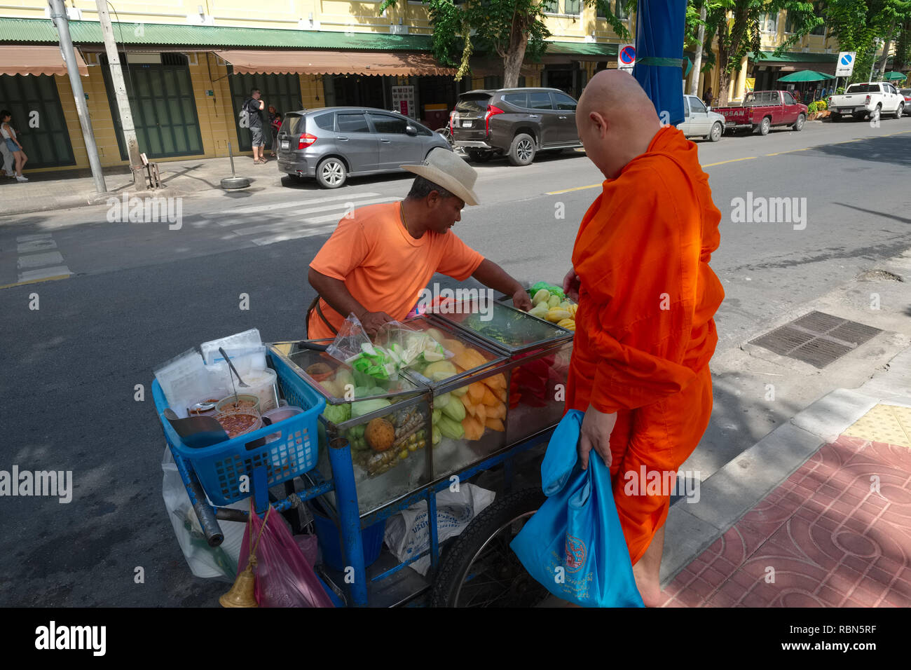 Ein buddhistischer Mönch in Bangkok, Thailand, Kauf von Obst aus einer mobilen Obst Anbieter; am frühen Morgen; Mönche sind nicht erlaubt nach Mittag zu essen Stockfoto