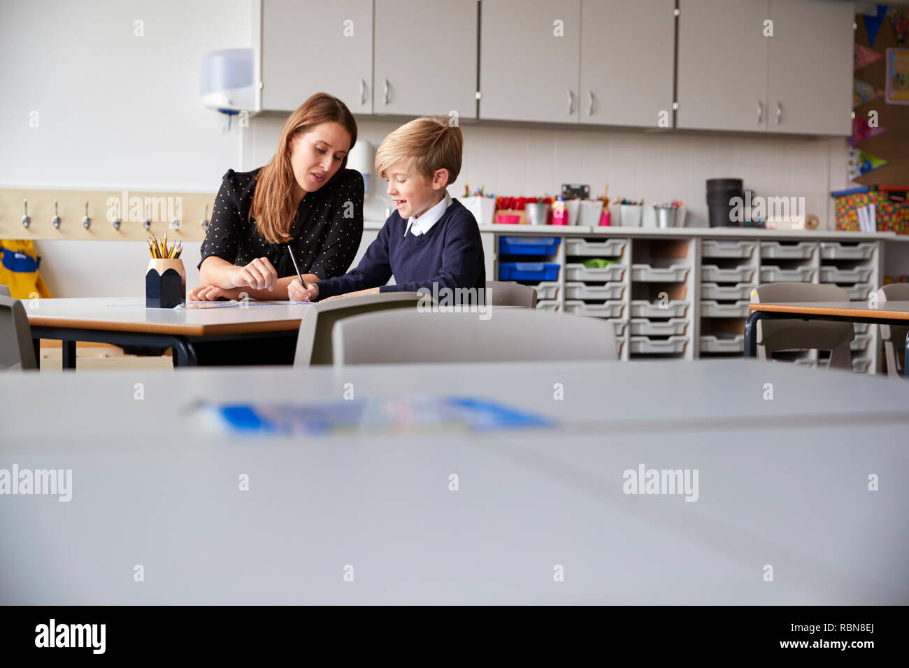 Junge weibliche Lehrer und Schüler an einem Tisch sitzen, auf einem selektiven Fokus Stockfoto