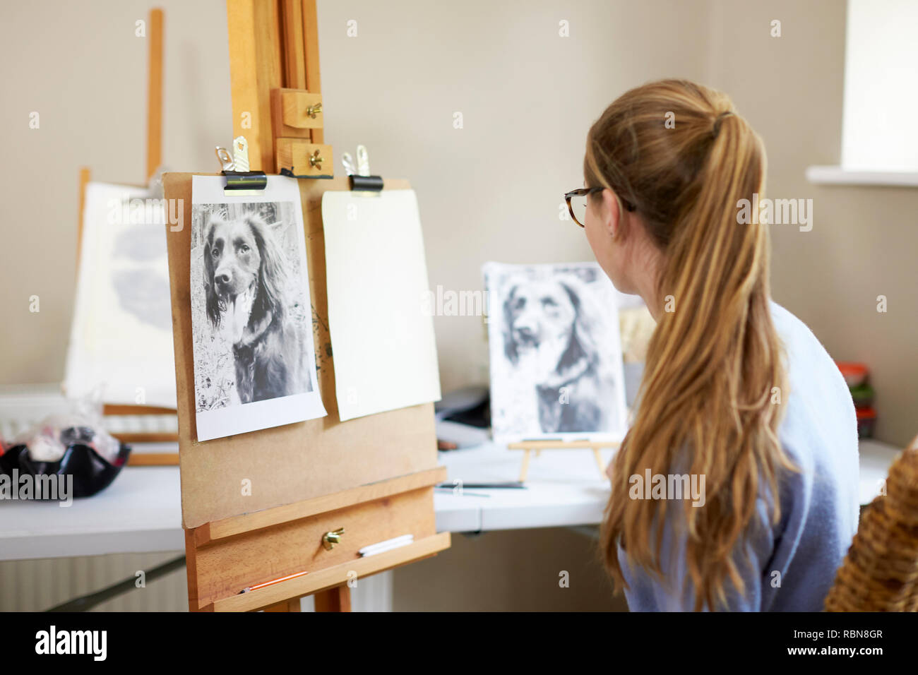 Weibliche Teenager Künstler sitzen an Staffelei Vorbereitung zu Zeichnen Bild von Hund von Foto Stockfoto
