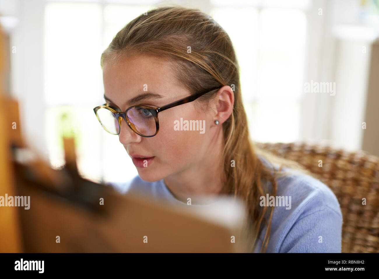 Weibliche Teenager Künstler sitzen an Staffelei Zeichnung Bild Stockfoto