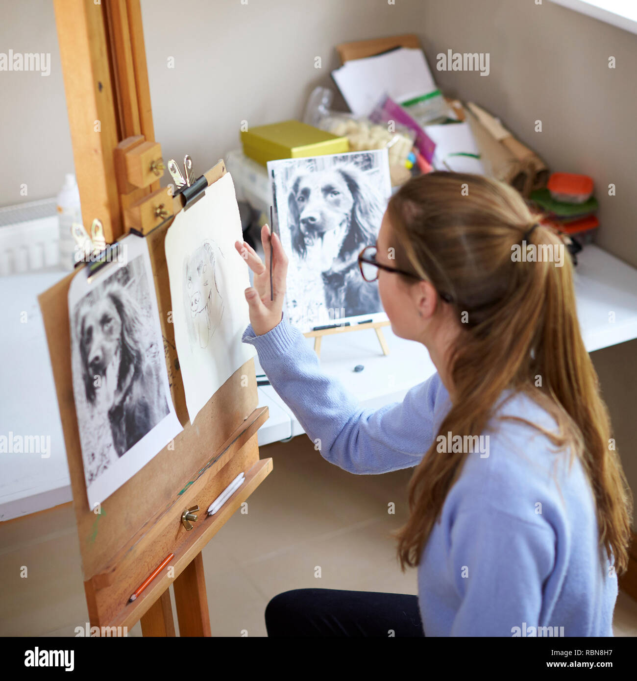 Weibliche Teenager Künstler sitzen an Staffelei Zeichnung Bild von Hund von Foto in Anthrazit Stockfoto