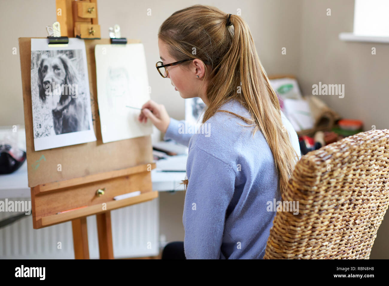 Weibliche Teenager Künstler sitzen an Staffelei Zeichnung Bild von Hund von Foto in Anthrazit Stockfoto