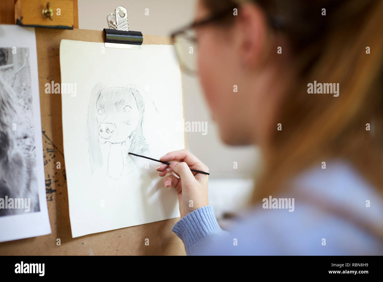In der Nähe der weiblichen Teenager Künstler sitzen an Staffelei Zeichnung Bild von Hund von Foto in Anthrazit Stockfoto