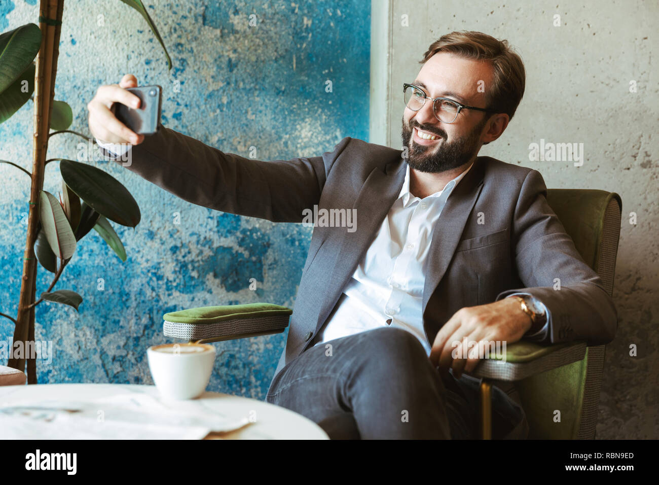 Lächeln, Geschäftsmann, tragen, Klage, eine selfie während im Cafe sitzen und Kaffee trinken Stockfoto