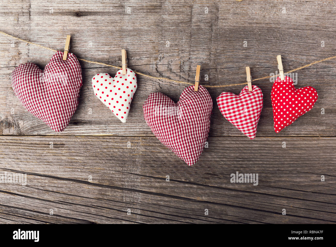 Schönen Valentines Tag textile Herz hängt am Seil auf alten hölzernen Hintergrund. Blick von oben. Valentines Tag Konzept. Stockfoto