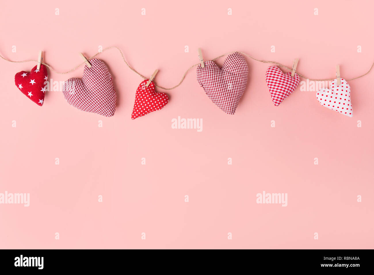 Schönen Valentines Tag textile Herz hängt am Seil auf rosa Hintergrund. Blick von oben. Valentines Tag Konzept. Stockfoto