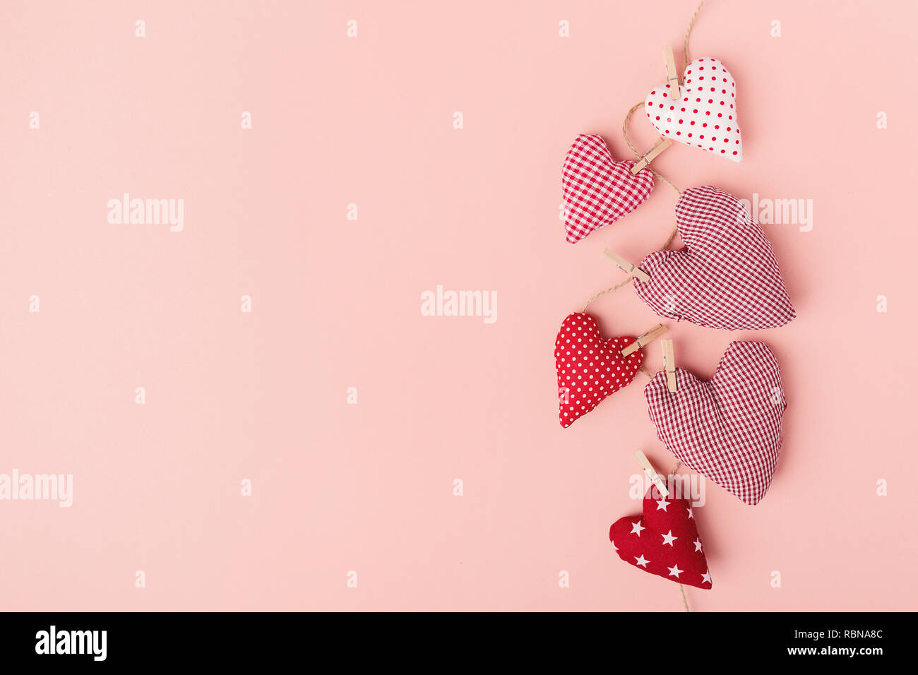 Schönen Valentines Tag textile Herz hängt am Seil auf rosa Hintergrund. Blick von oben. Valentines Tag Konzept. Stockfoto