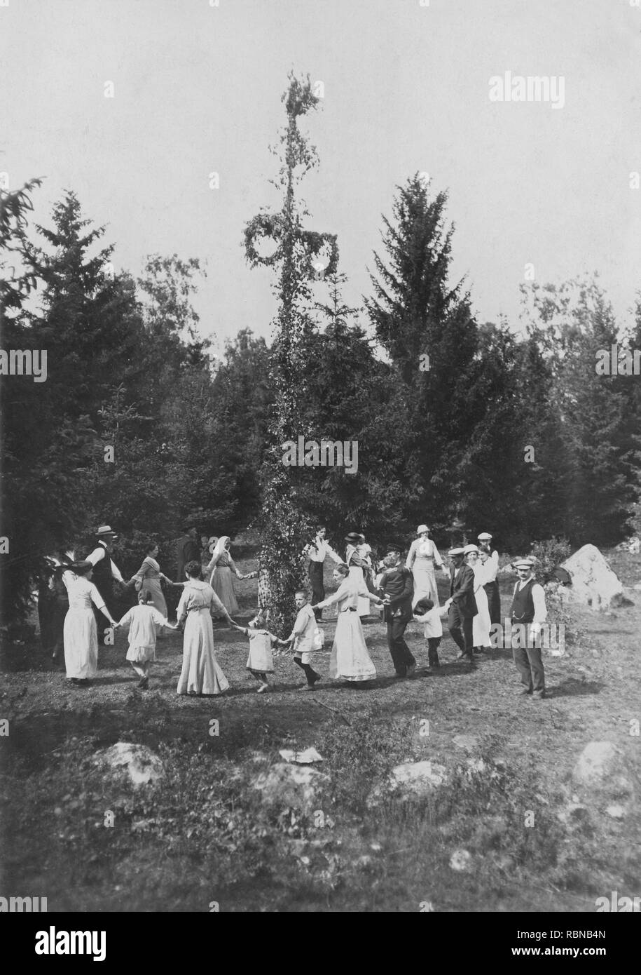 Mittsommer Tradition in Schweden. Als Teil der Festlichkeiten einen Maibaum ist auferstanden, Männer, Frauen und Kinder versammeln sich um ihn zu tanzen. Schweden zu Beginn des 20. Jahrhunderts. Stockfoto