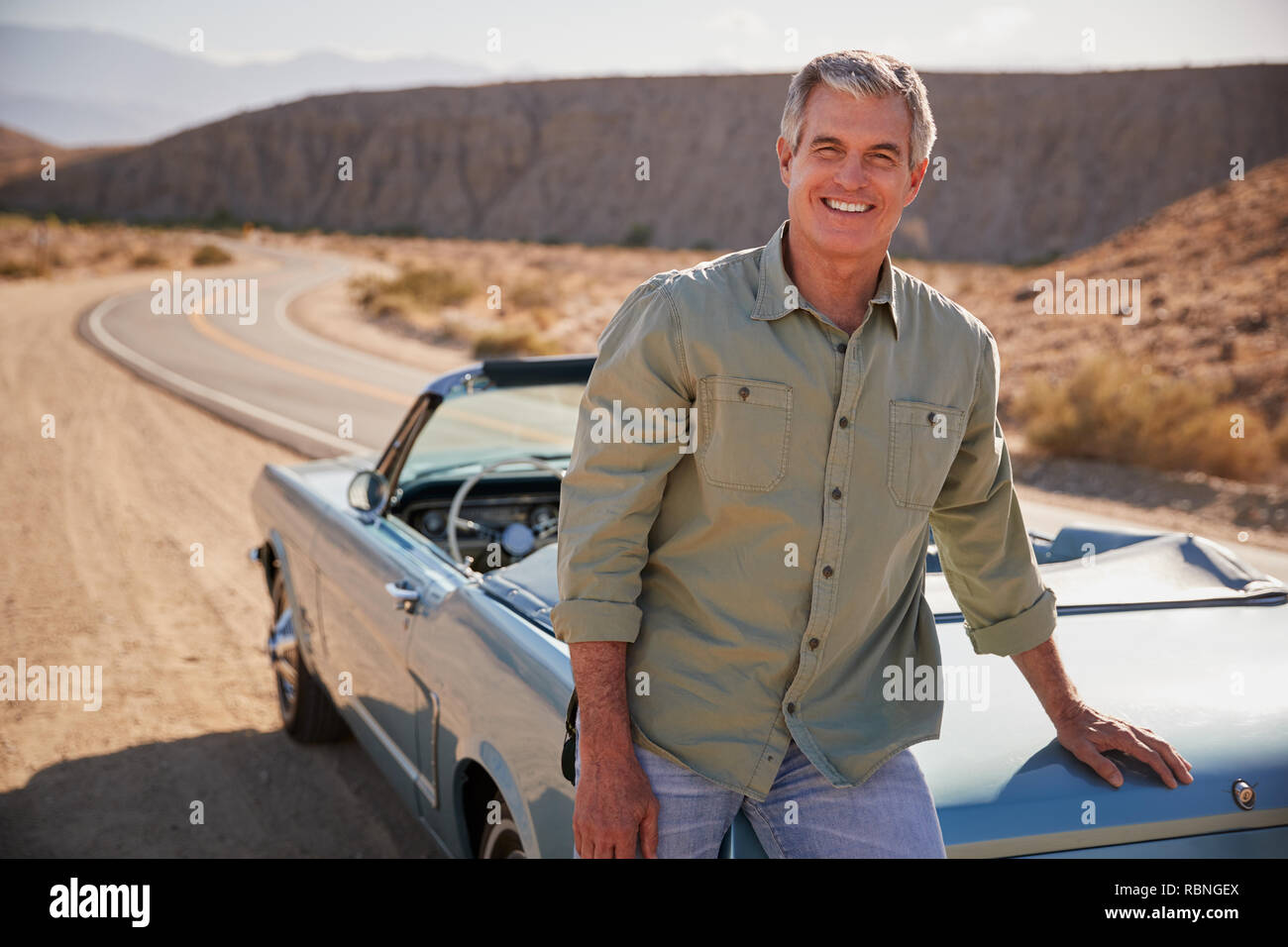 Senior weiße Mann lehnte sich auf oben offenen Auto, das an der Wüste am Straßenrand Stockfoto