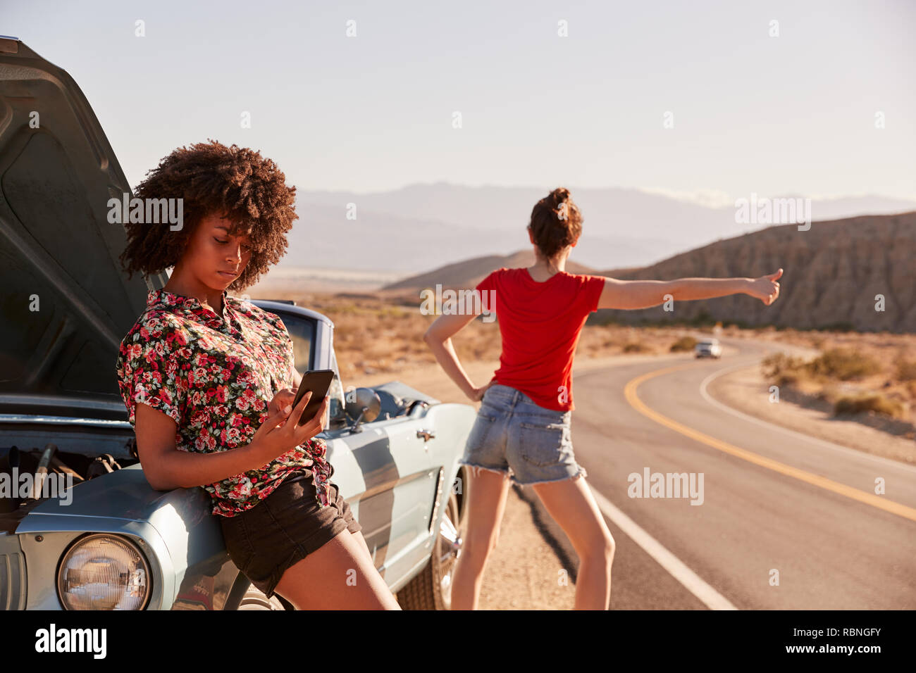 Zwei weibliche Freunde durch Ihre aufgeschlüsselt Auto am Straßenrand Stockfoto