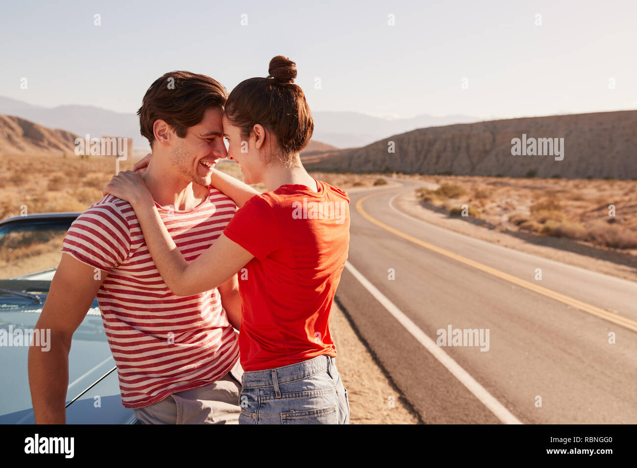 Junge weiße Paar umarmen, die ihr Fahrzeug am Straßenrand Stockfoto