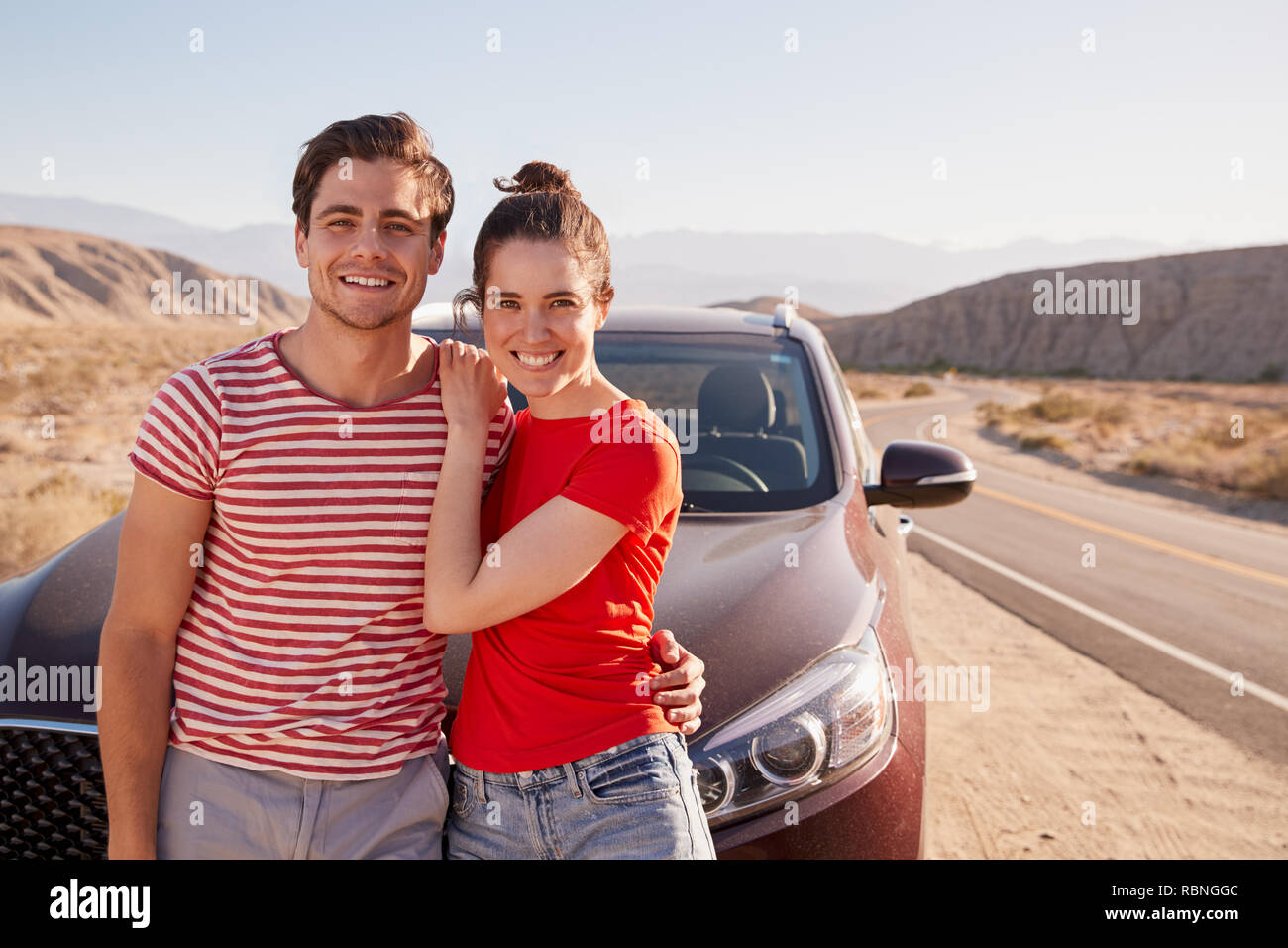 Junge weiße Paar stehend auf Wüste Straße mit dem Auto Stockfoto
