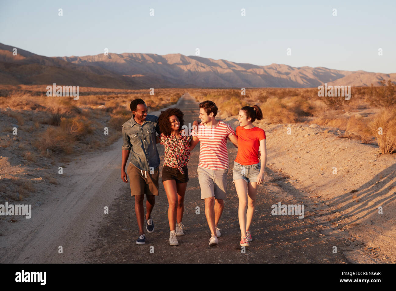 Vier junge erwachsene Freunde sprechen, als sie in der Wüste zu Fuß Stockfoto