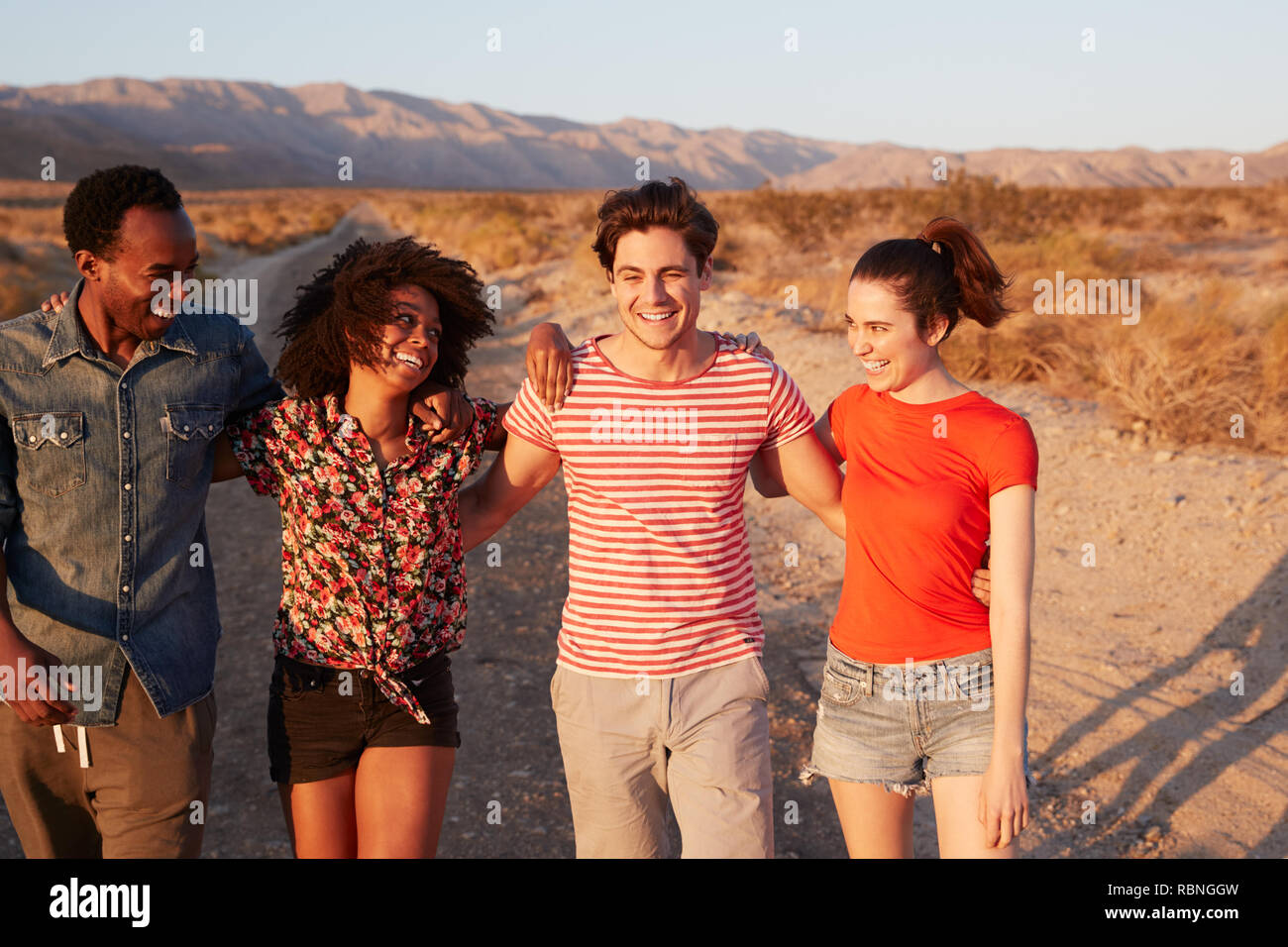 Vier junge erwachsene Freunde lachen auf einer einsamen Straße, in der Nähe Stockfoto