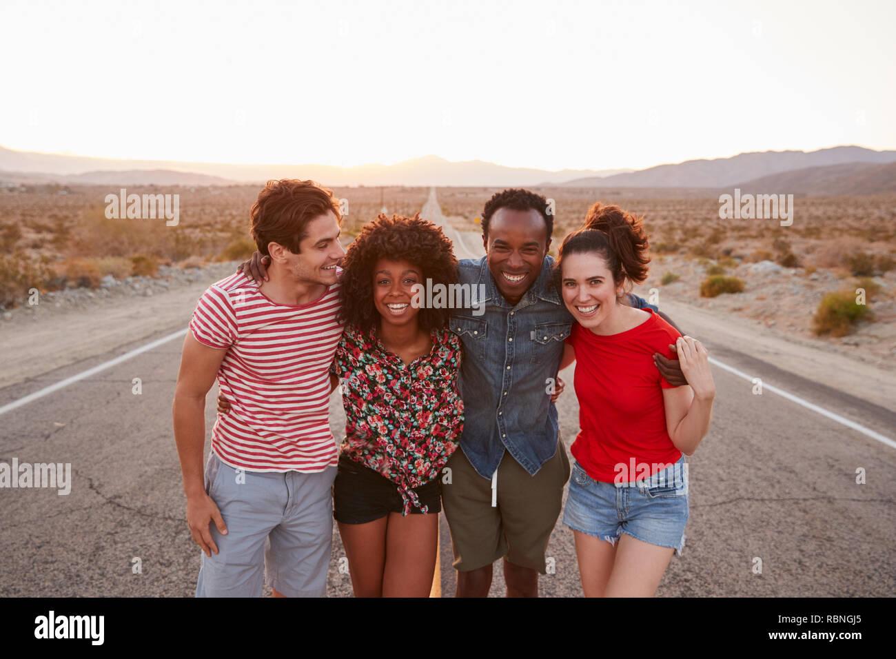 Vier glückliche Freunde stehen auf einer einsamen Landstraße, in der Nähe Stockfoto