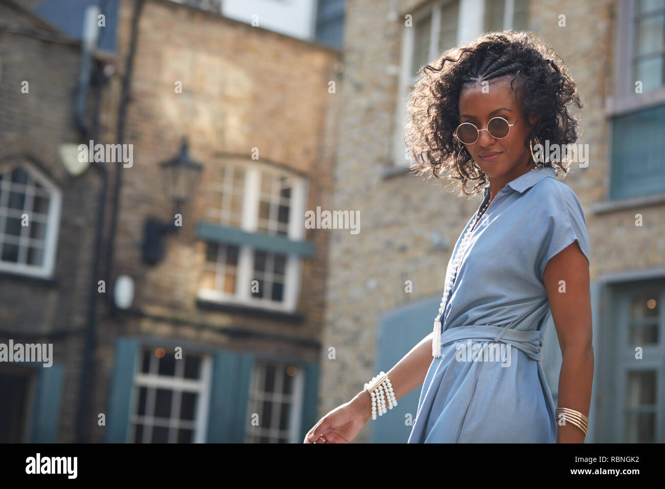 Trendy Frau in Blau angeschnittene Ärmel Kleid und Sonnenbrille Stockfoto