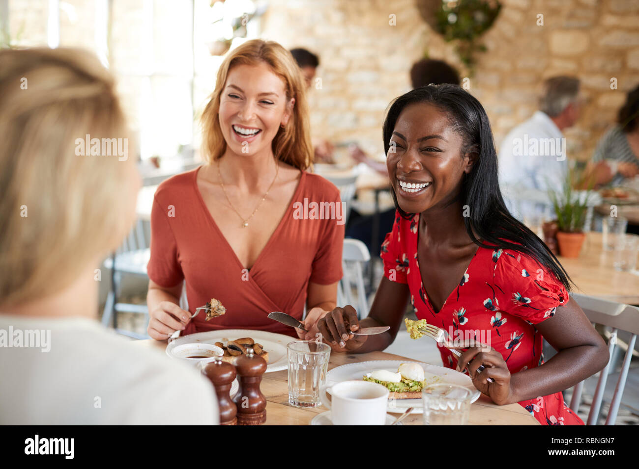Junge weibliche Freunde lächelnd beim Brunch im Cafe, in der Nähe Stockfoto
