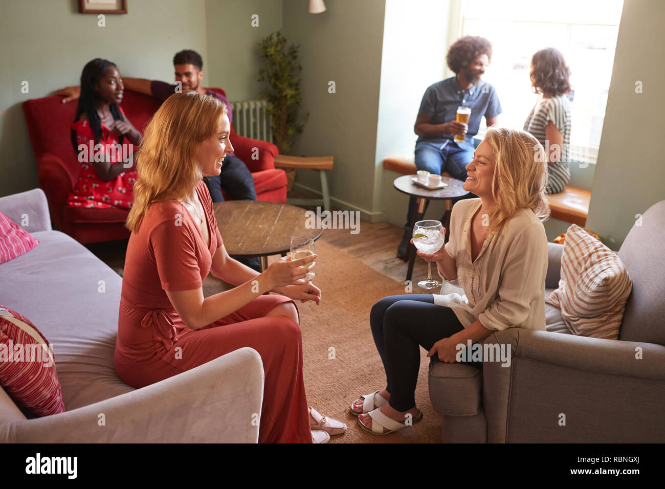 Zwei weibliche Freunde sprechen und sich einen Drink in einem Pub Stockfoto