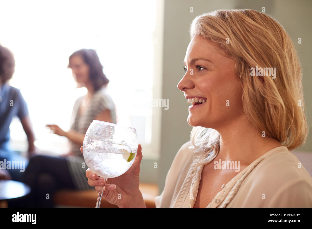 Nahaufnahme der jungen Frau mit einem Drink in einem Pub, Seitenansicht Stockfoto