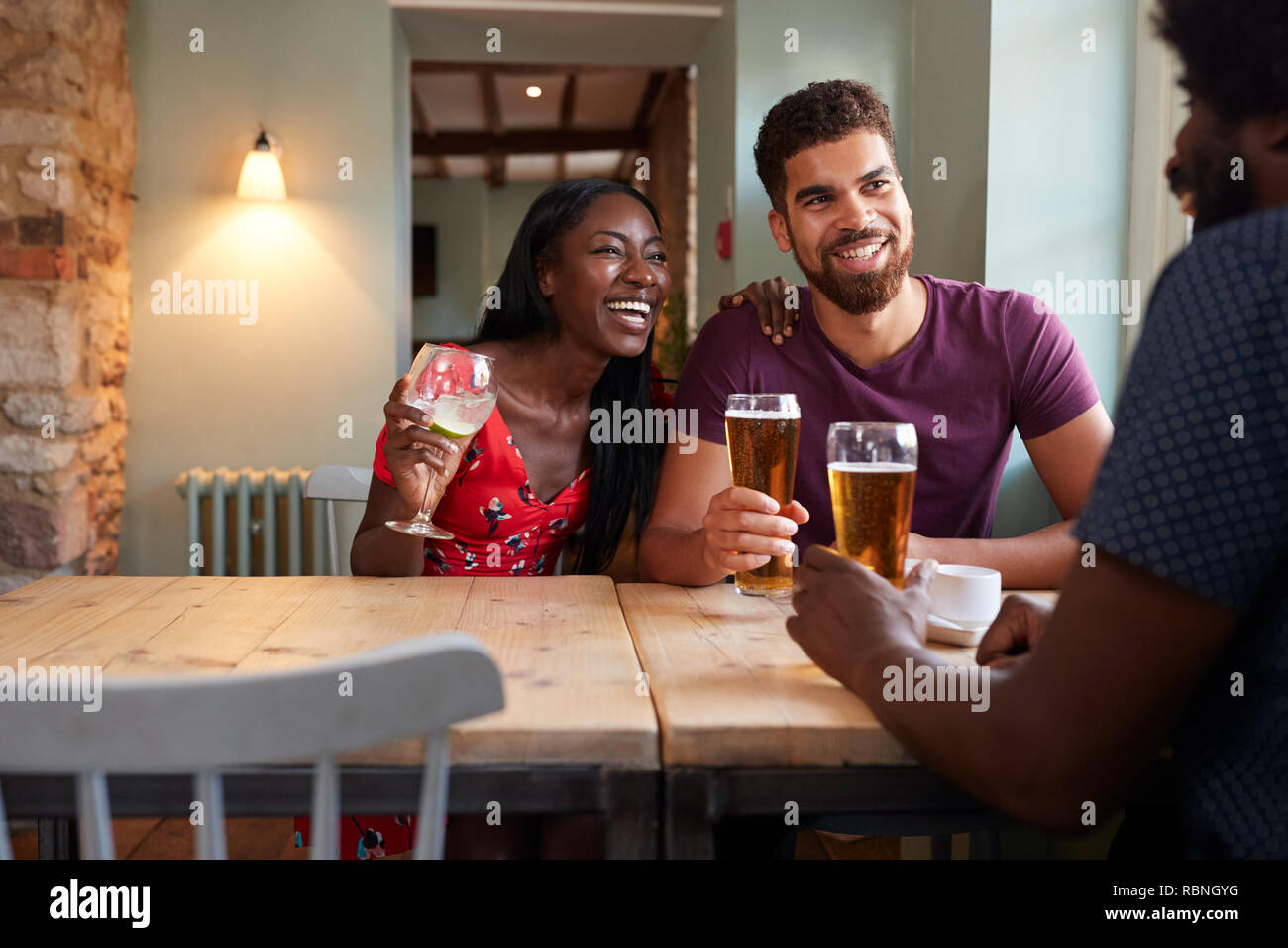 Junges Paar und ein älterer Mann trinken an einem Tisch in einer Kneipe Stockfoto