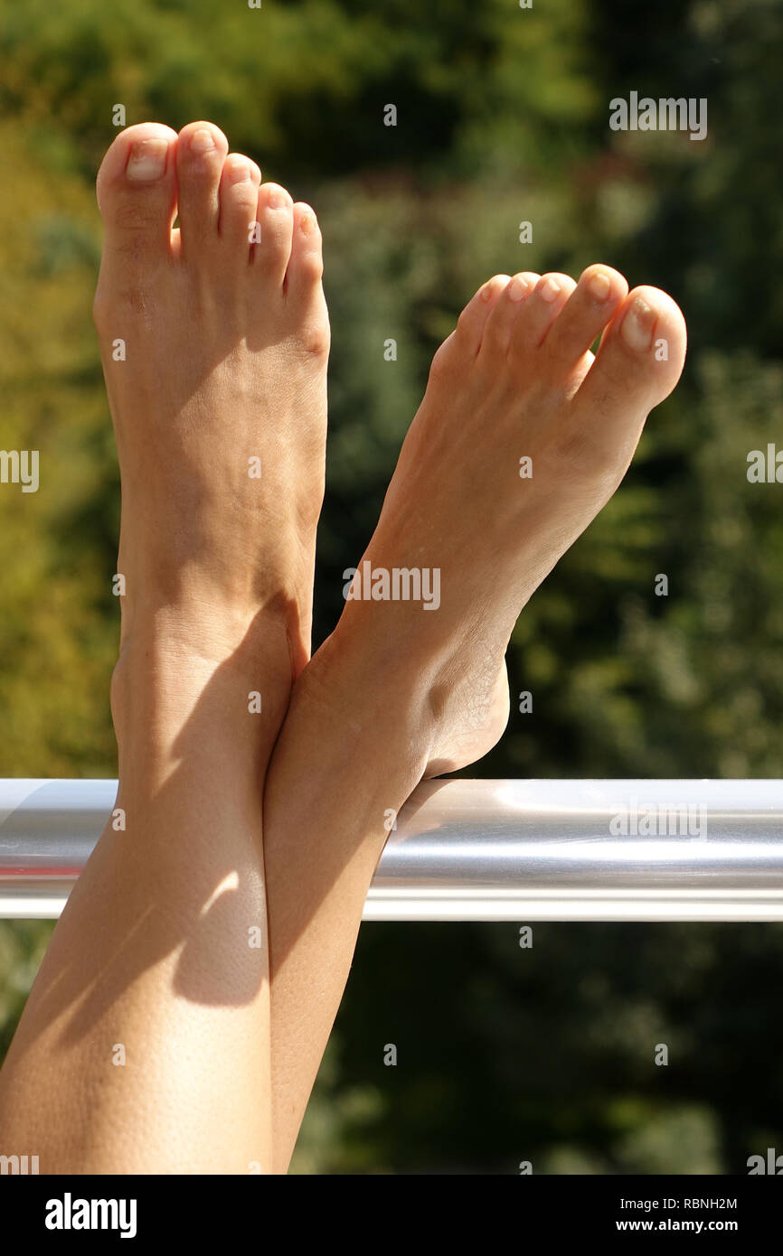Frau hält Ihren Fuß oben in der Sonne, vertikale full frame Stockfoto