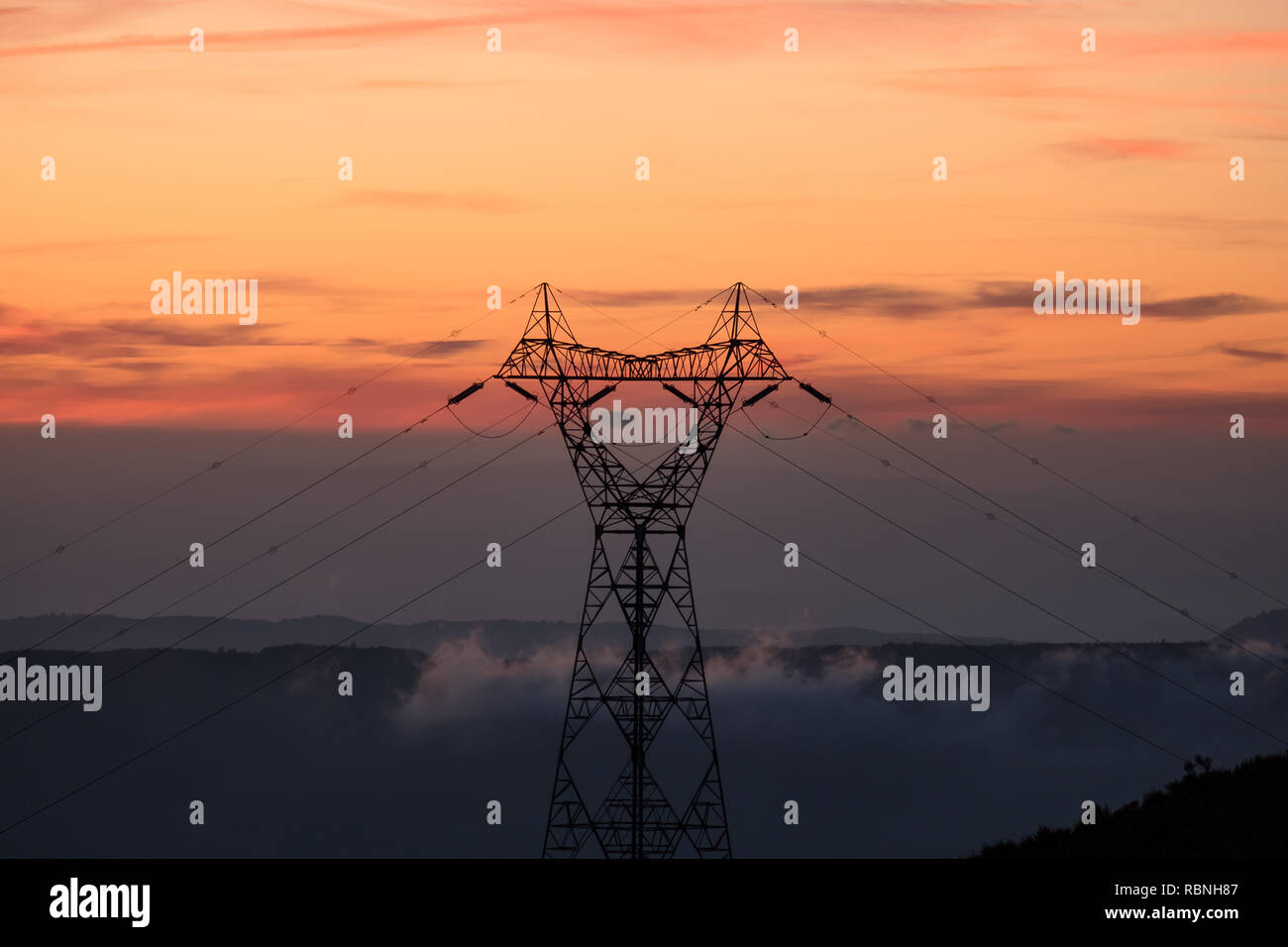 Elektrische Turm mit Bergen im Hintergrund, während Sie im Sonnenuntergang Stockfoto