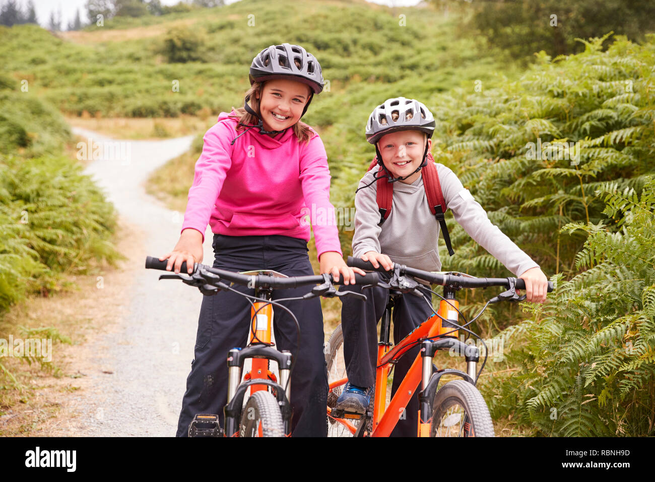 Zwei Kinder sitzen auf ihren Mountainbikes auf ein Land weg lachen, Vorderansicht Stockfoto
