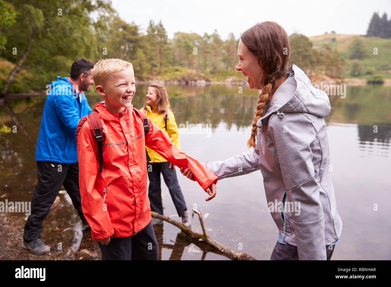 Junge Familie Spielen mit Ihren Kindern am Ufer eines Sees, in der Nähe, Lake District, Großbritannien Stockfoto