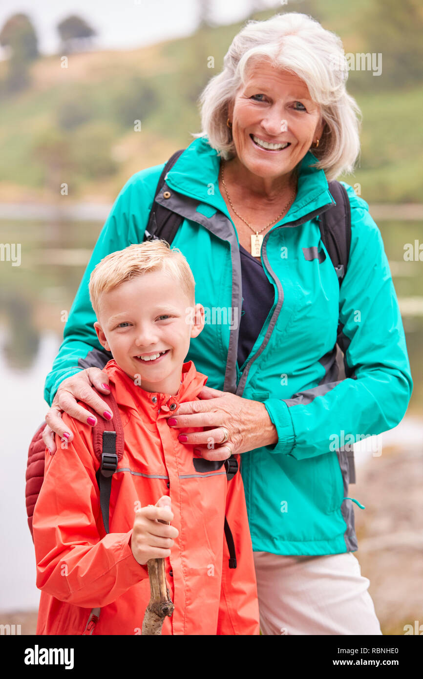 Großmutter und Enkel gemeinsam in der Nähe von einem See in der Landschaft lächelnd in die Kamera, Nahaufnahme, Lake District, Großbritannien Stockfoto