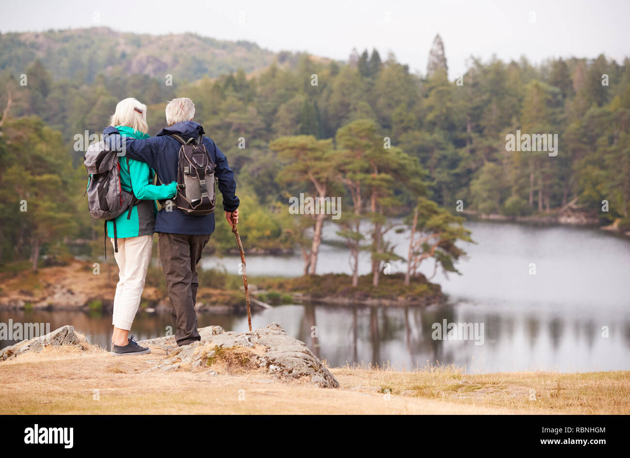 Senior Paar ständigen umarmen und bewundern Sie die Aussicht auf einen See, Rückansicht Stockfoto