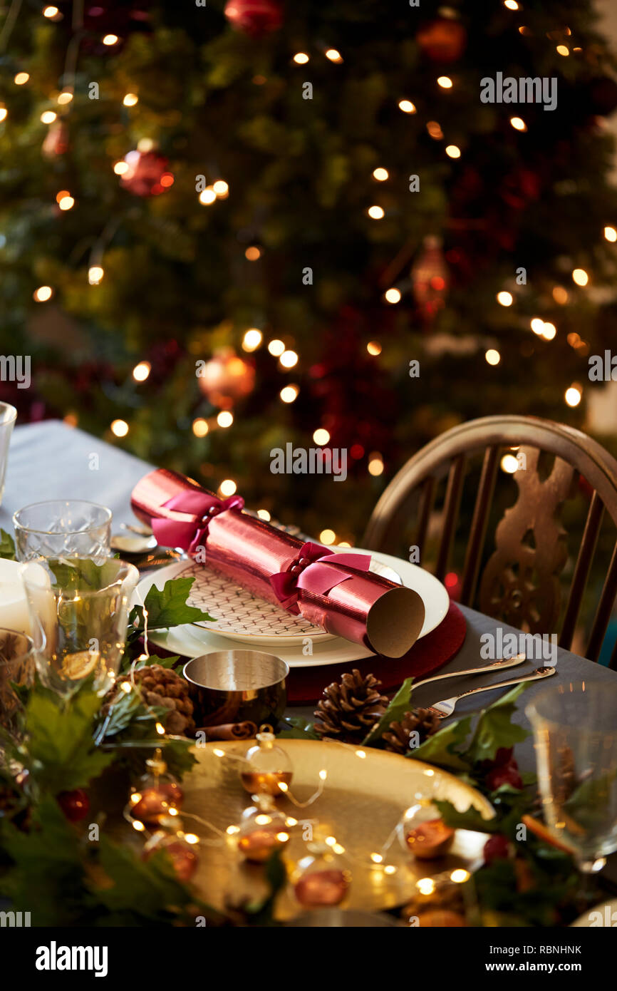 Weihnachten Tabelle ein mit Christmas Cracker auf einer Platte und Tischdekorationen angeordnet, ein Weihnachtsbaum im Hintergrund Stockfoto