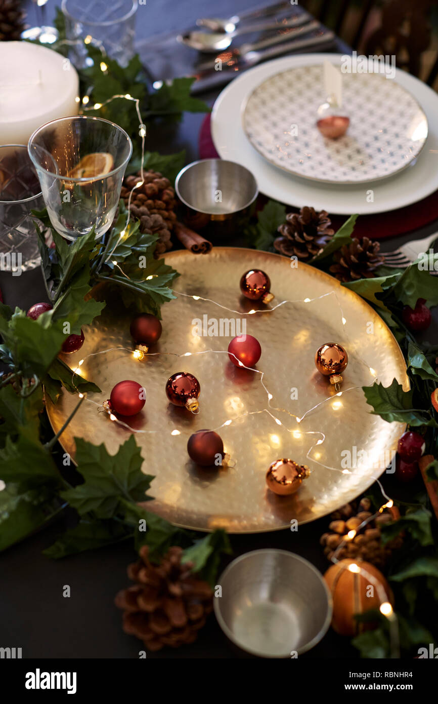 Weihnachten Tischdekoration mit Kugeln auf goldene Platte, christbaumkugel Name Kartenhalter auf Platte und grün und rot Dekorationen arrangiert, in der Nähe Stockfoto