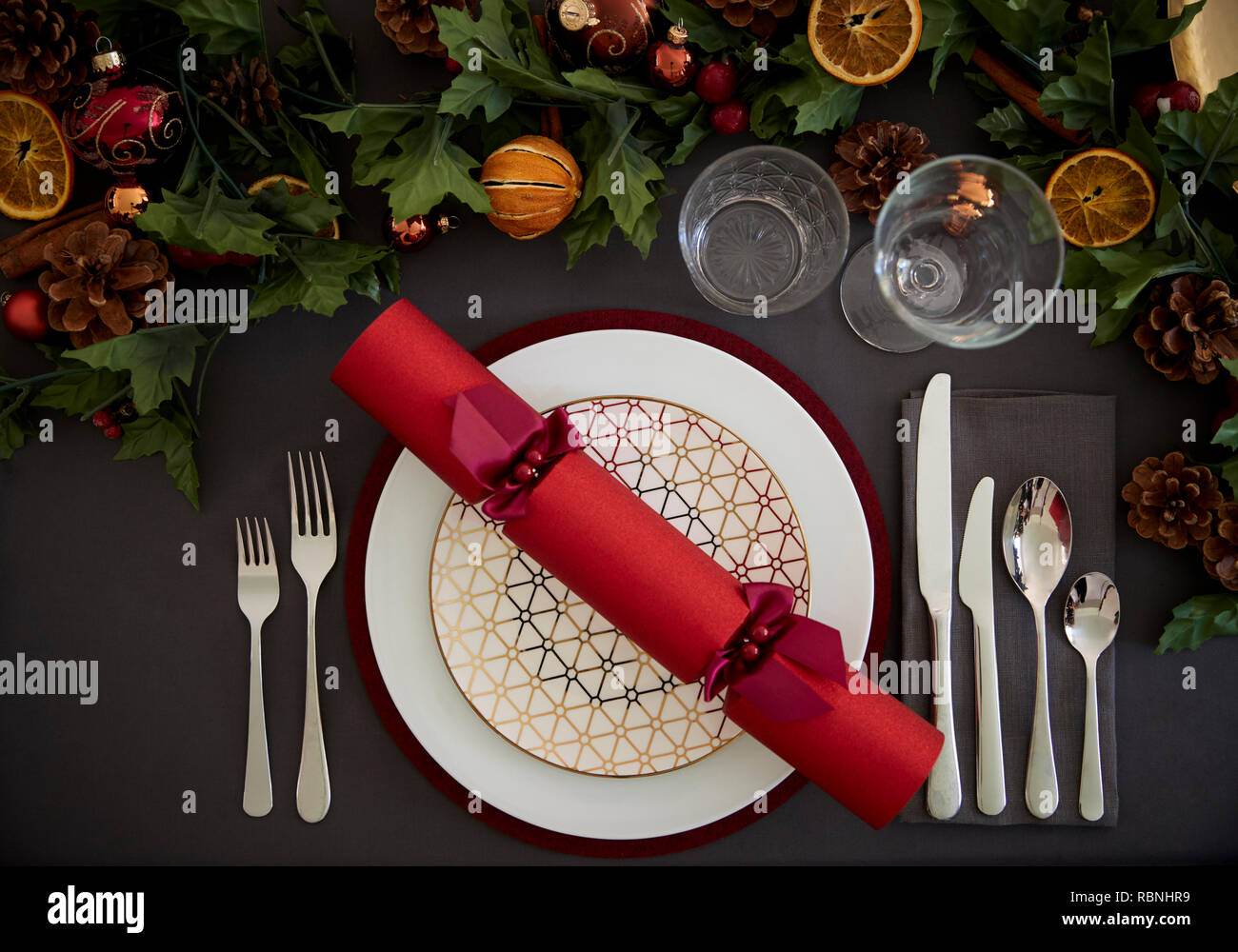 Weihnachten Tabelle Einstellung mit einem roten Christmas Cracker auf einer Platte und Grün und Rot Tischdekoration angeordnet, Ansicht von oben Stockfoto