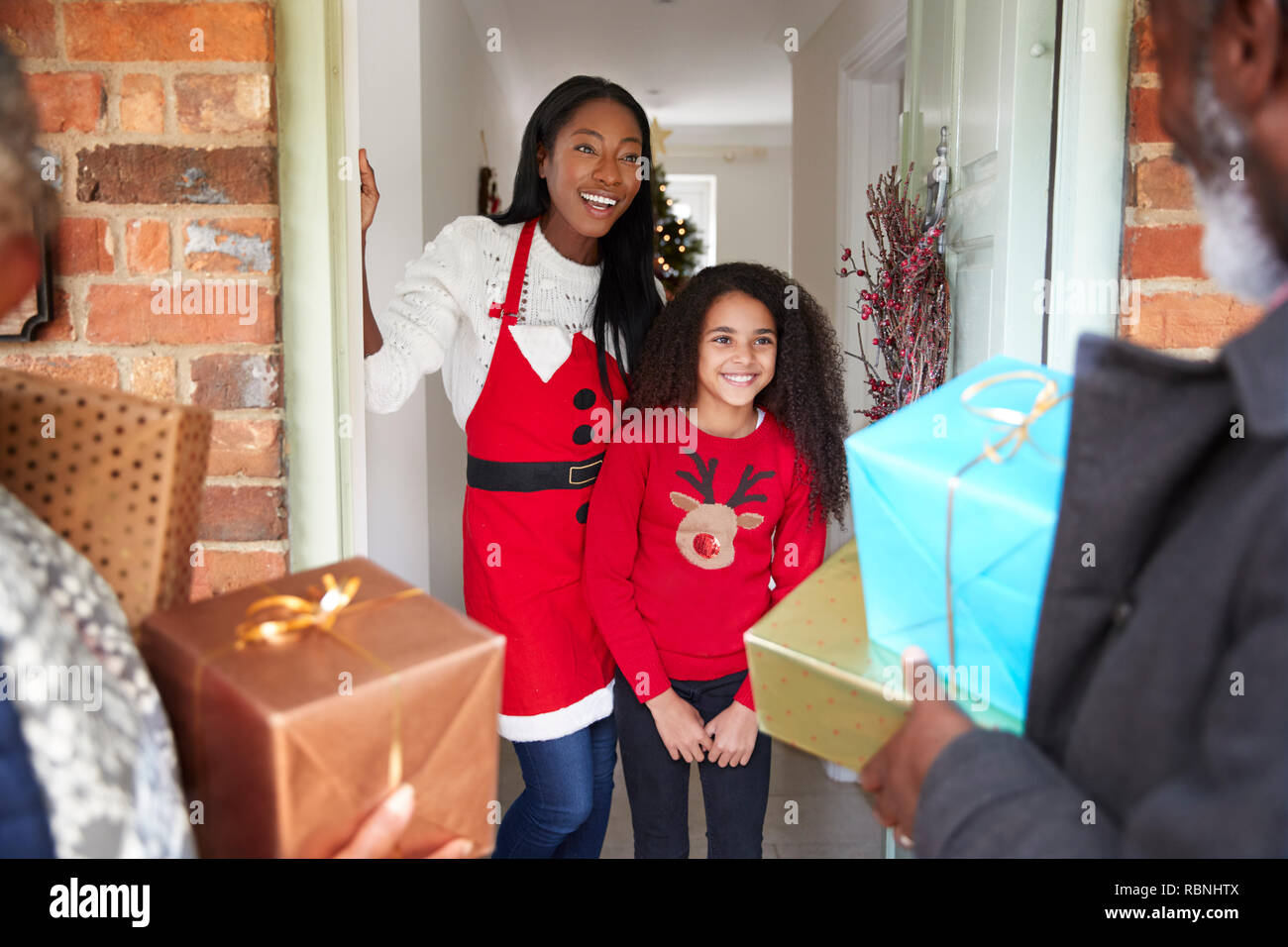 Die großeltern von Mutter und Tochter begrüßt, wie Sie ankommen zu besuchen und an Weihnachten mit Geschenken Stockfoto