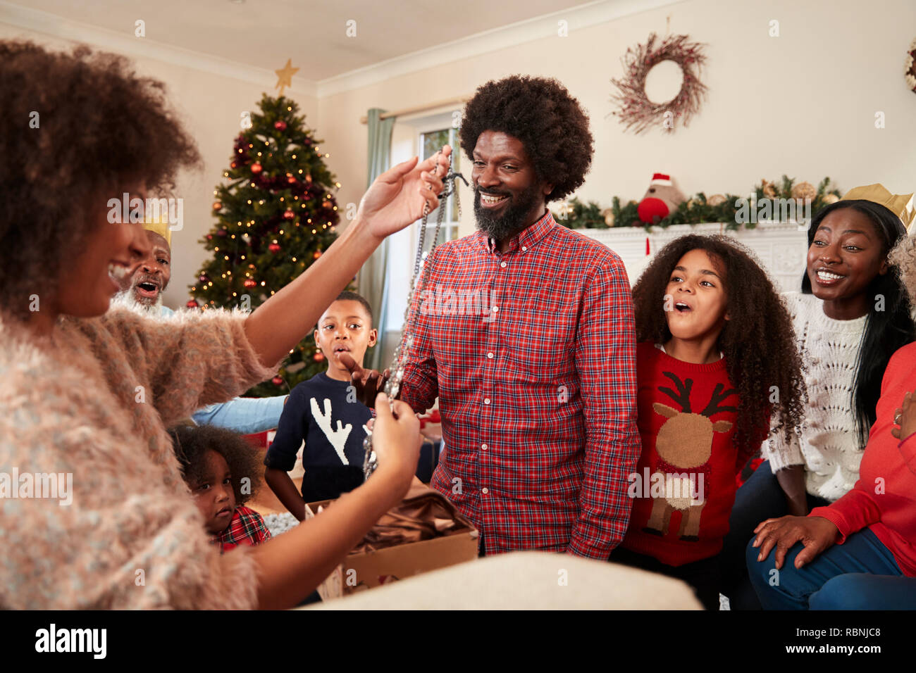 Paar den Austausch von Geschenken wie Multi-Generation Familie Weihnachten feiern zu Hause zusammen Stockfoto