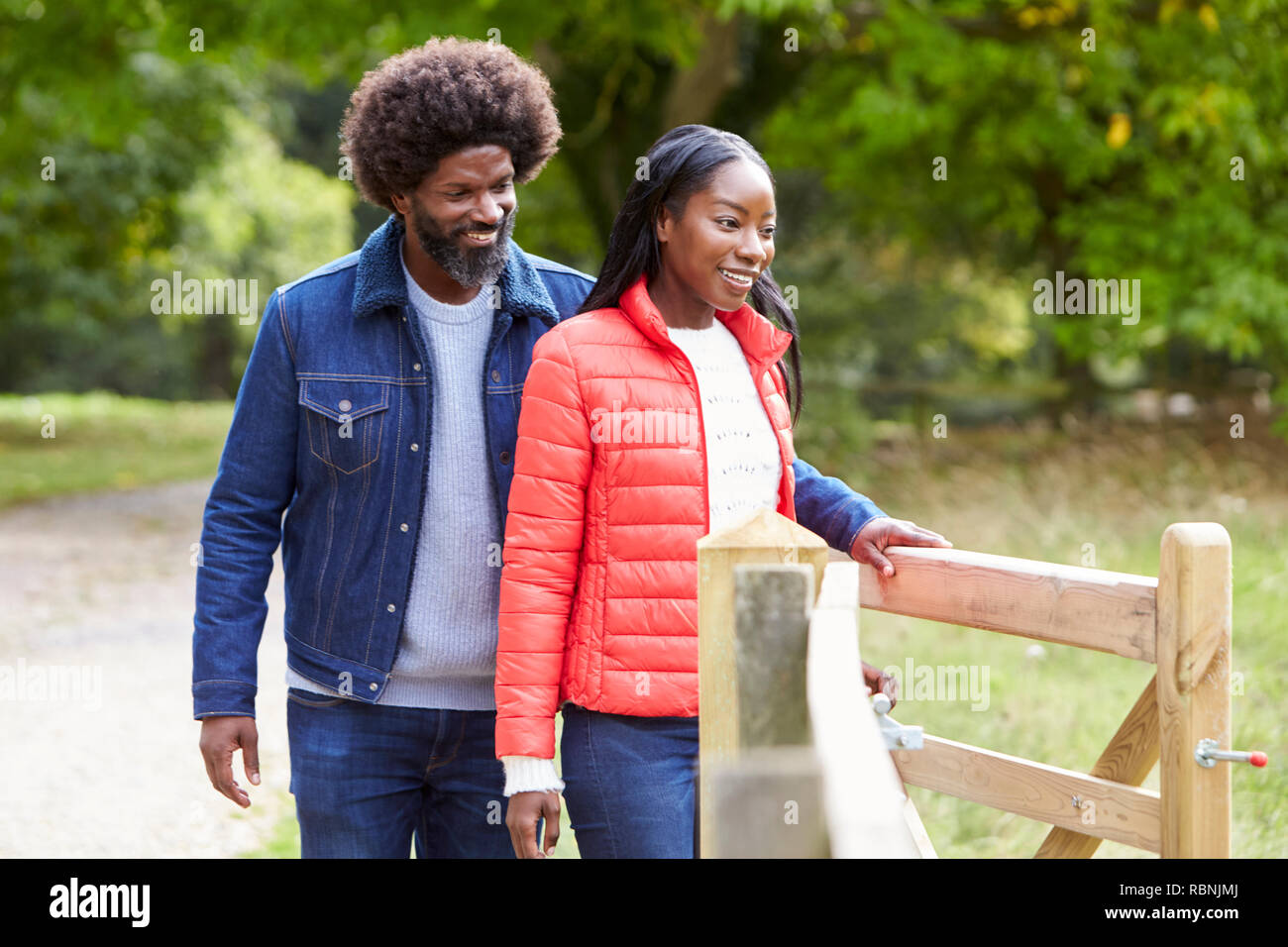 Mann Öffnen eines Tores für seine Freundin bei einem Spaziergang in dem Land, in der Nähe Stockfoto