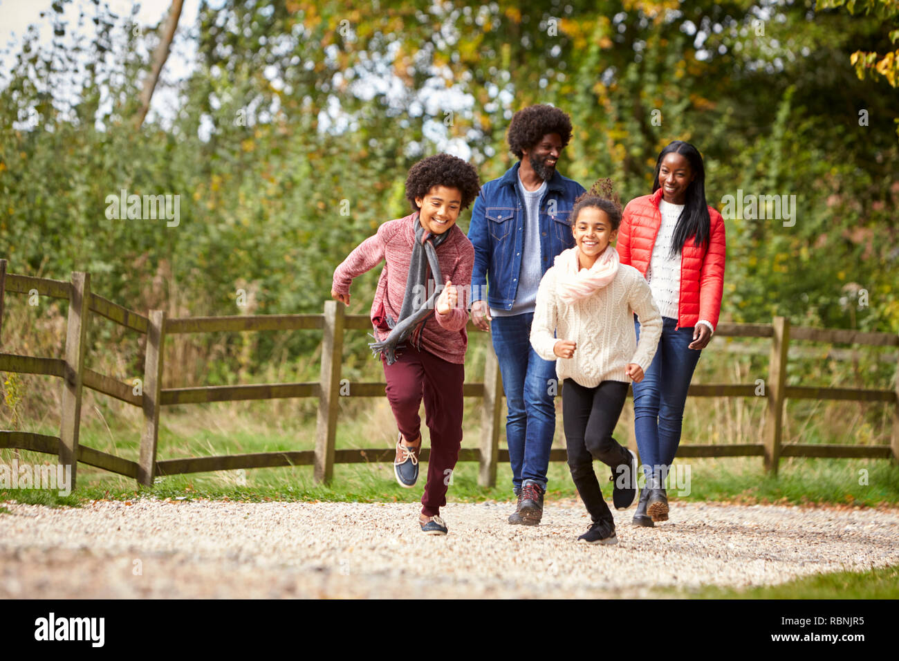 Gemischten rennen Kinder vor ihren Eltern auf einem Pfad während Familie Spaziergang auf dem Land, in der niedrigen Winkel Stockfoto