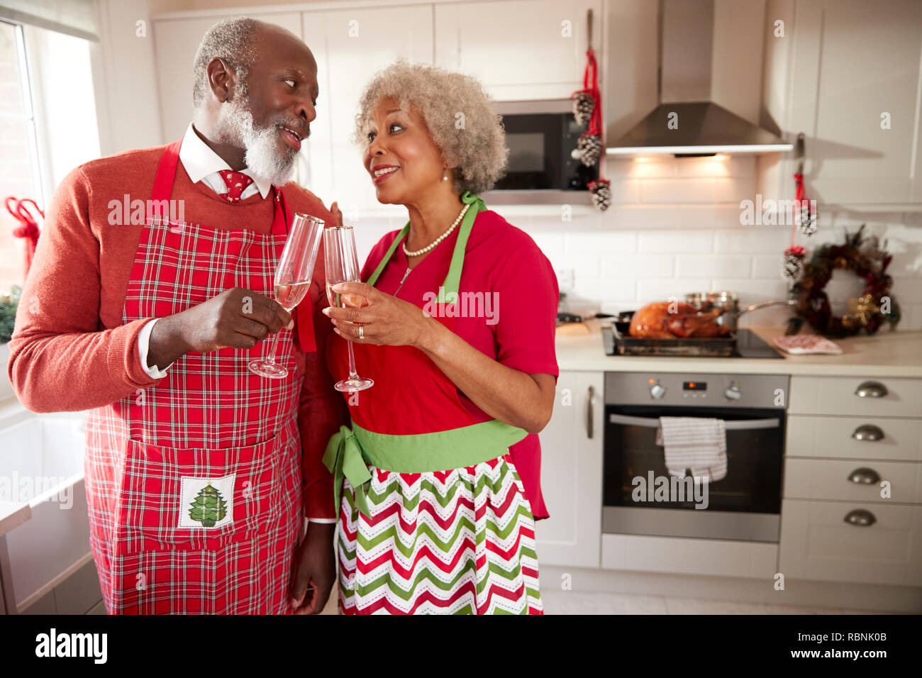 Senior schwarz Paar Schürzen tragen eine Pause von der Vorbereitung Weihnachtsessen einen Toast zu machen, in der Nähe Stockfoto