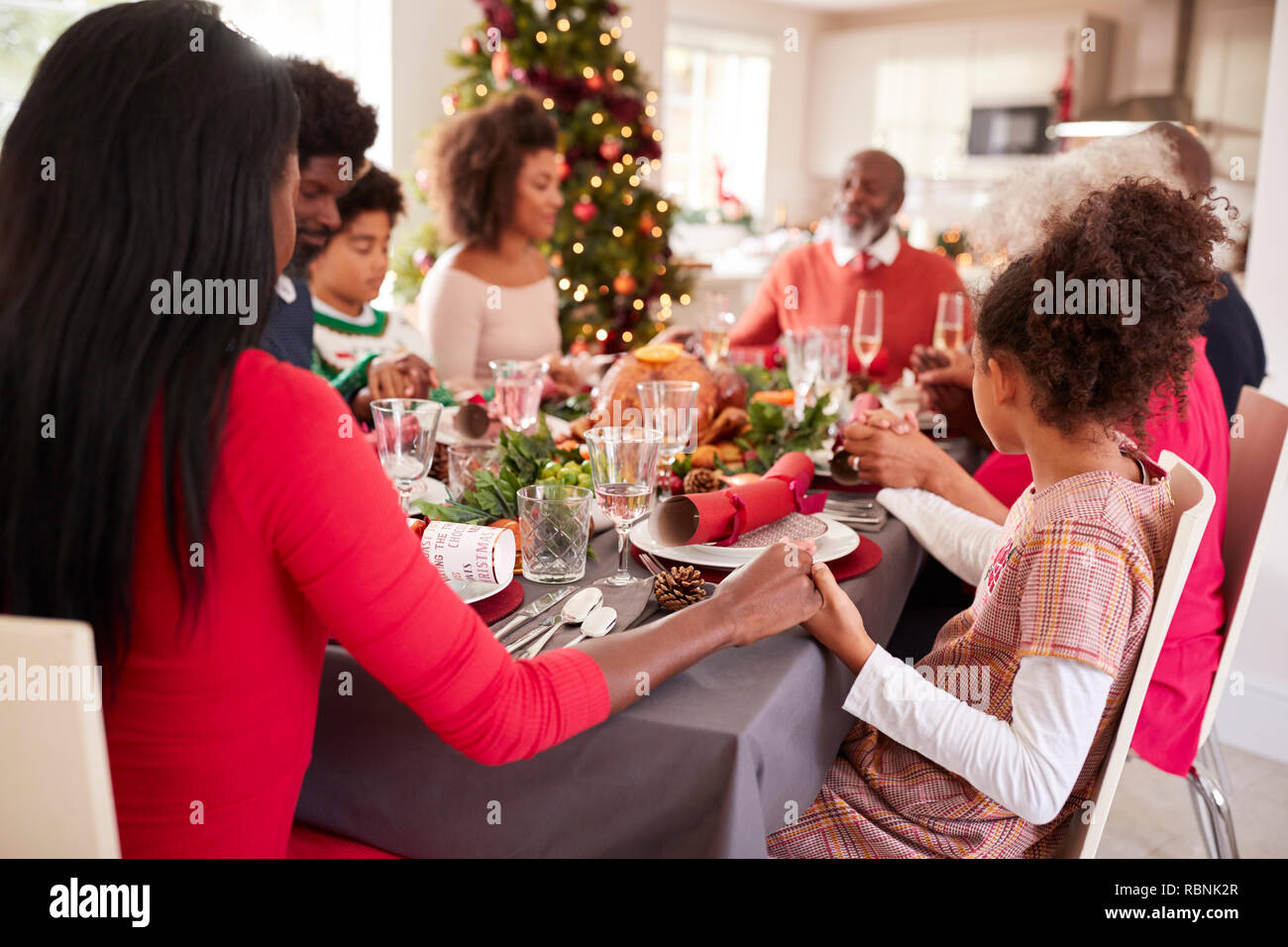 Multi-Generation, gemischten Rennen Familie halten sich an den Händen und sagen Gnade am Weihnachtsessen Tabelle, Seitenansicht Stockfoto
