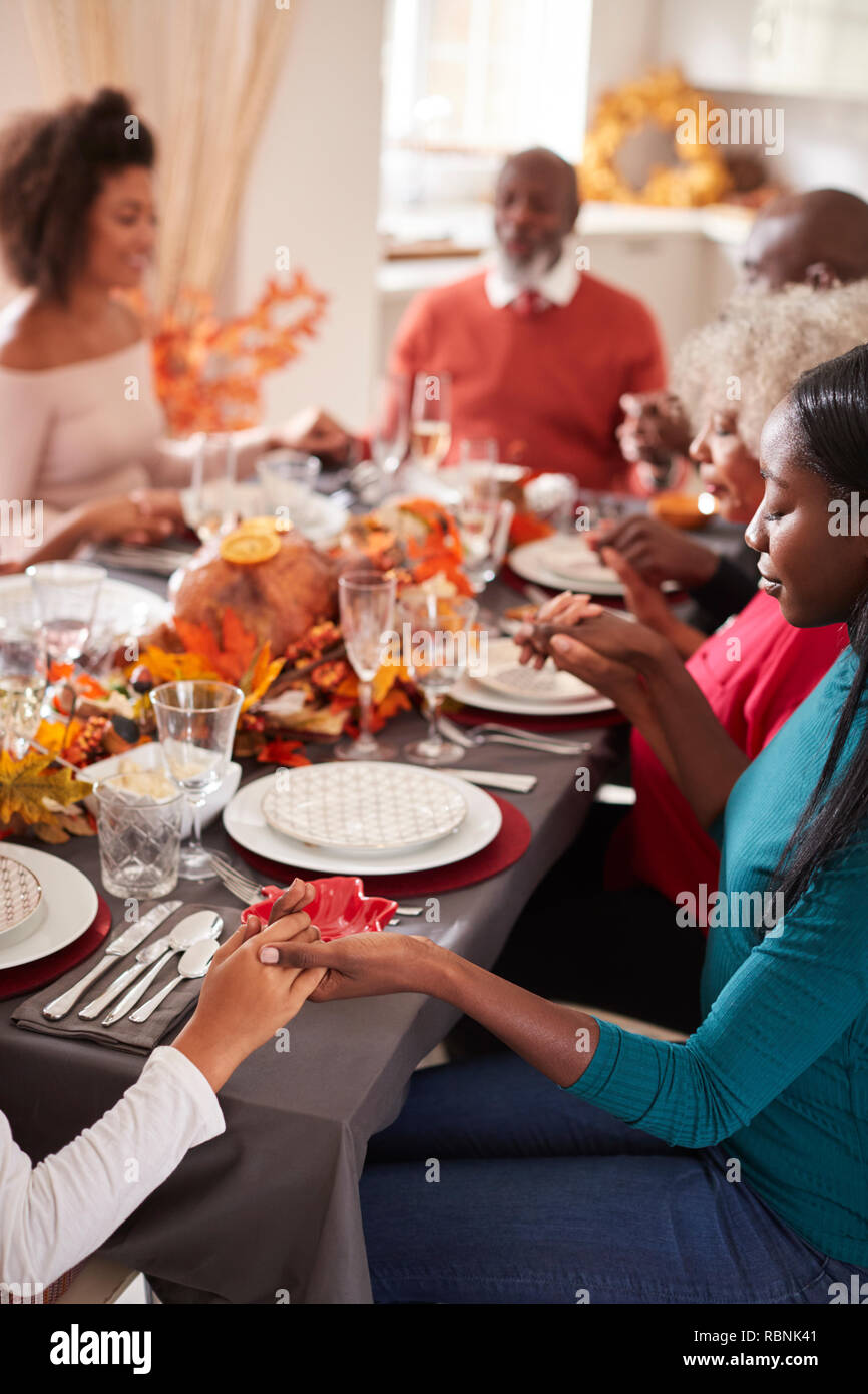 Multi-Generation gemischten Rennen Familie halten sich an den Händen und sagen Gnade vor dem Essen am Thanksgiving Dinner Table, selektiver Fokus, vertikal Stockfoto