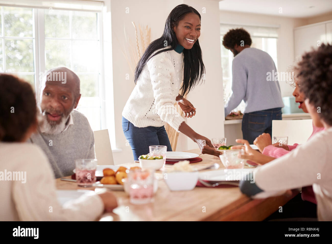 Schwarz Paar bringen das Essen an den Tisch für Sonntag Abendessen mit der Familie für die Kinder und Großeltern. Stockfoto