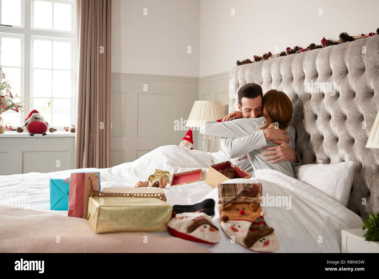 Paar Schmusen im Bett zu Hause, da sie den Datenaustausch Geschenke an Weihnachten Stockfoto